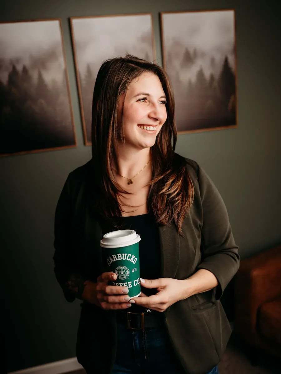 Jess Orr in her Wooster office, holding a coffee and smiling